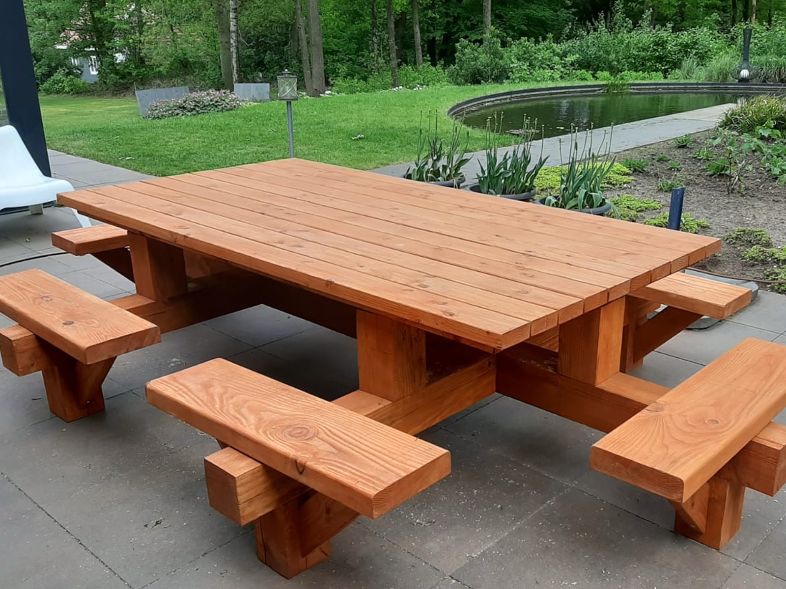 Massiver Picknicktisch aus Douglasienholz auf einer Terrasse am Gartenteich